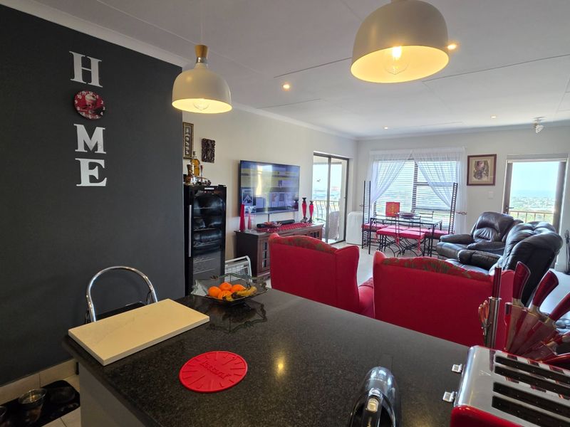 Spacious open-plan living area featuring a kitchen with granite countertops, flowing into a lounge with access to a balcony through sliding glass doors.