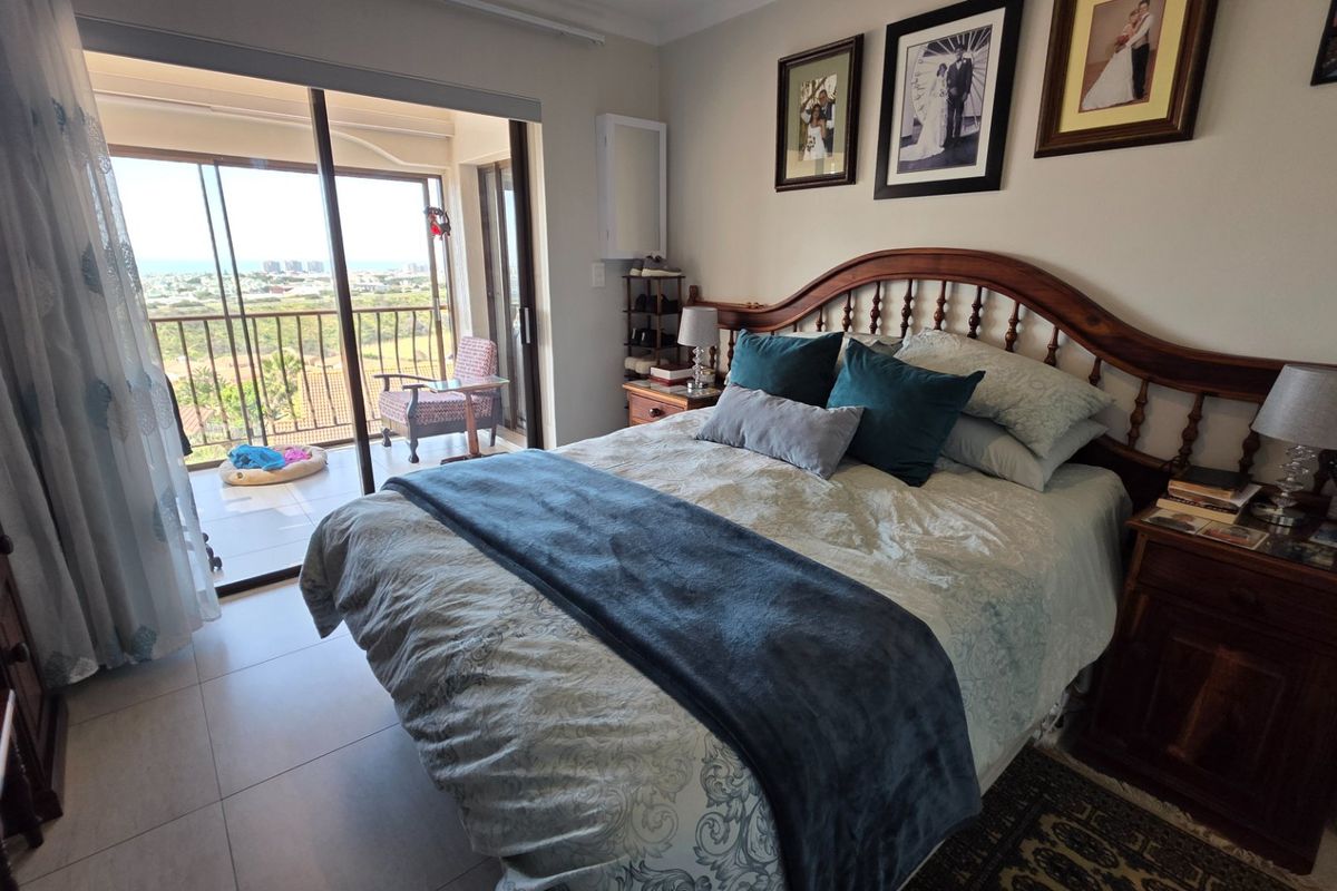 A well-maintained bedroom featuring tiled flooring and large sliding glass doors that open onto a private balcony with scenic views.