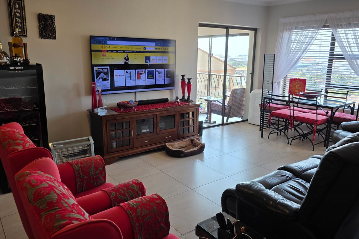 A spacious living room featuring tiled flooring, large windows, and a sliding glass door providing access to an outdoor balcony area.