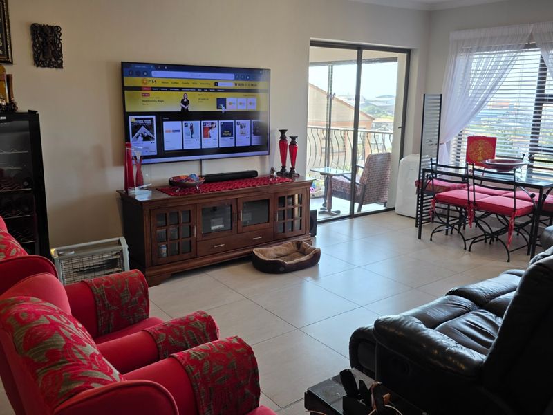 A spacious living room featuring tiled flooring, large windows, and a sliding glass door providing access to an outdoor balcony area.