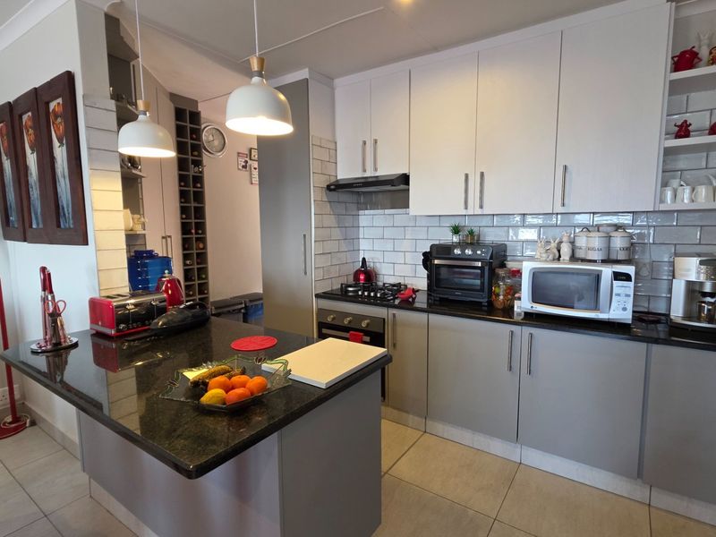 Modern kitchen featuring granite countertops, subway tile backsplash, built-in oven with gas hob, and a dedicated wine rack storage area.