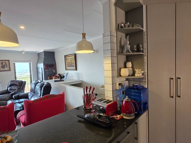 Open plan living area featuring a kitchen with granite countertops, built-in wine storage, and modern pendant lighting, flowing into a comfortable lounge space.