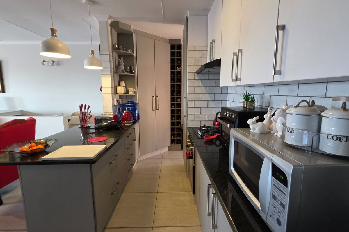 Modern kitchen featuring sleek grey and white cabinetry, granite countertops, subway tile backsplash, and a dedicated built-in wine rack.