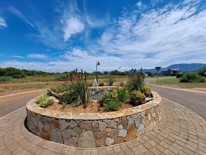 A landscaped circular stone planter with a central water fountain located within a residential estate setting.