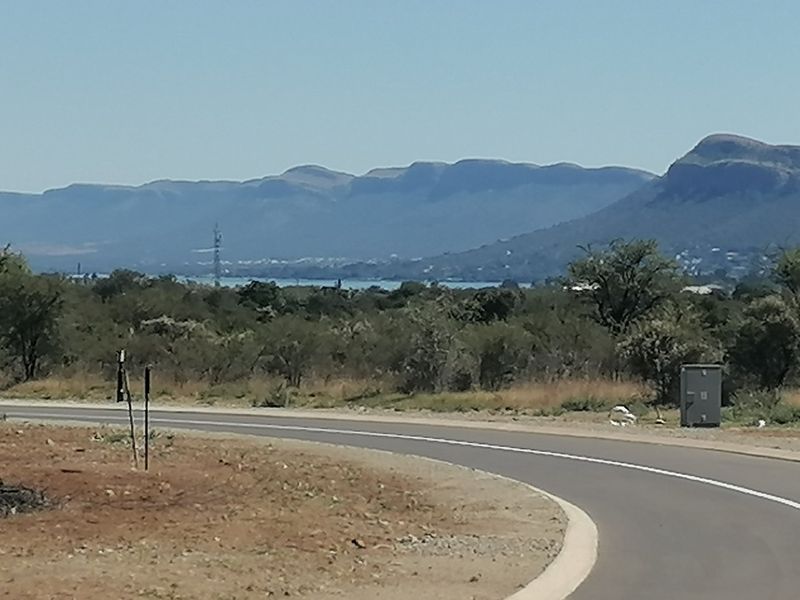 A scenic view of the surrounding landscape and mountains from the paved residential road.