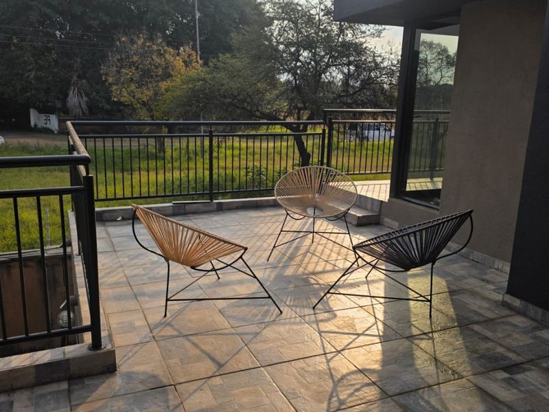 A spacious outdoor patio featuring tiled flooring and a secure metal balustrade, offering an open area suitable for relaxation.