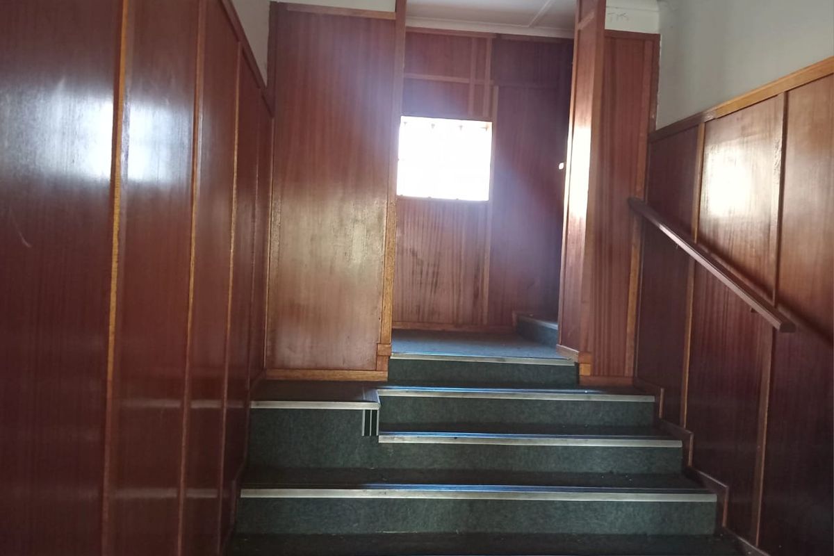A commercial hallway featuring timber wall paneling and a carpeted staircase with a fixed handrail.
