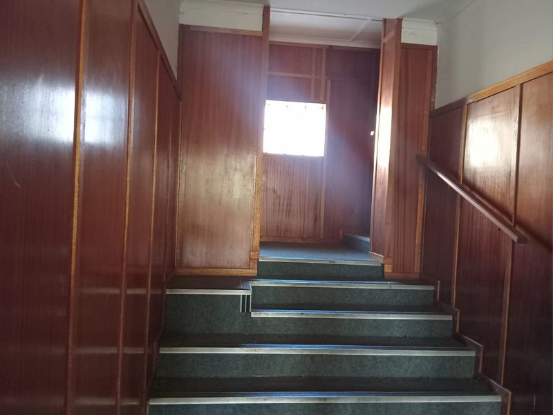 A commercial hallway featuring timber wall paneling and a carpeted staircase with a fixed handrail.