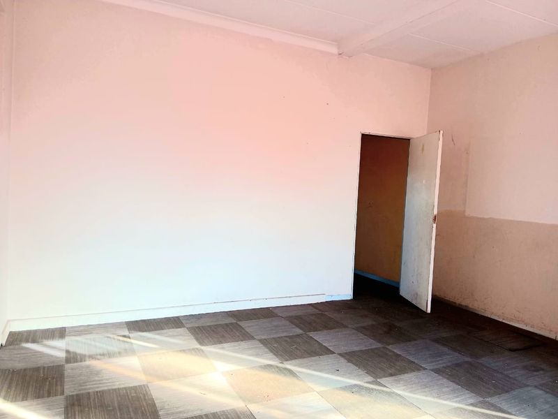 An empty commercial office space featuring tiled flooring and plain walls, suitable for a variety of business or professional uses.