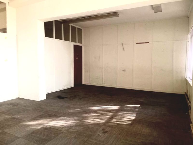 An empty commercial office space featuring carpet tiles, partition walls, and fluorescent lighting, requiring cosmetic updates and refurbishment.