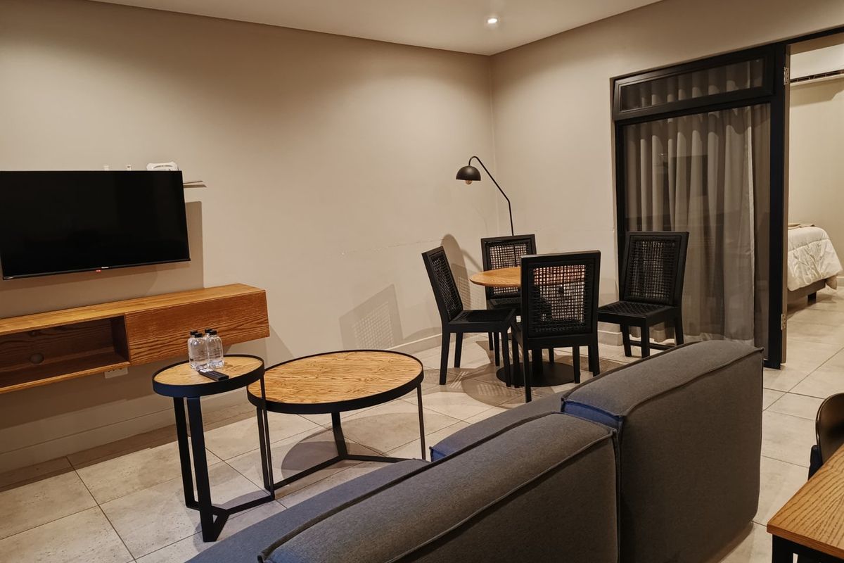 A modern living room featuring tiled flooring, a wall-mounted media console, and a sliding glass door leading to an adjacent space.