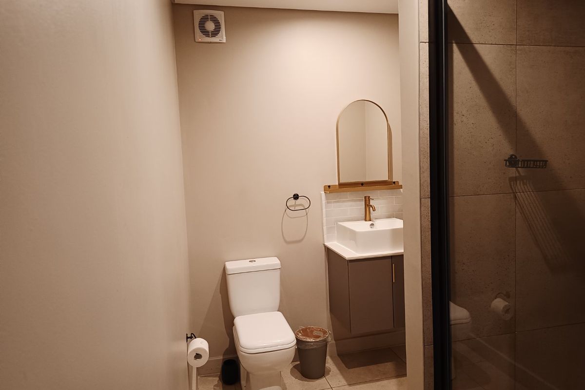 Modern bathroom featuring a vanity with vessel sink, brass fixtures, tiled flooring, and a glass-enclosed shower with neutral wall finishes.