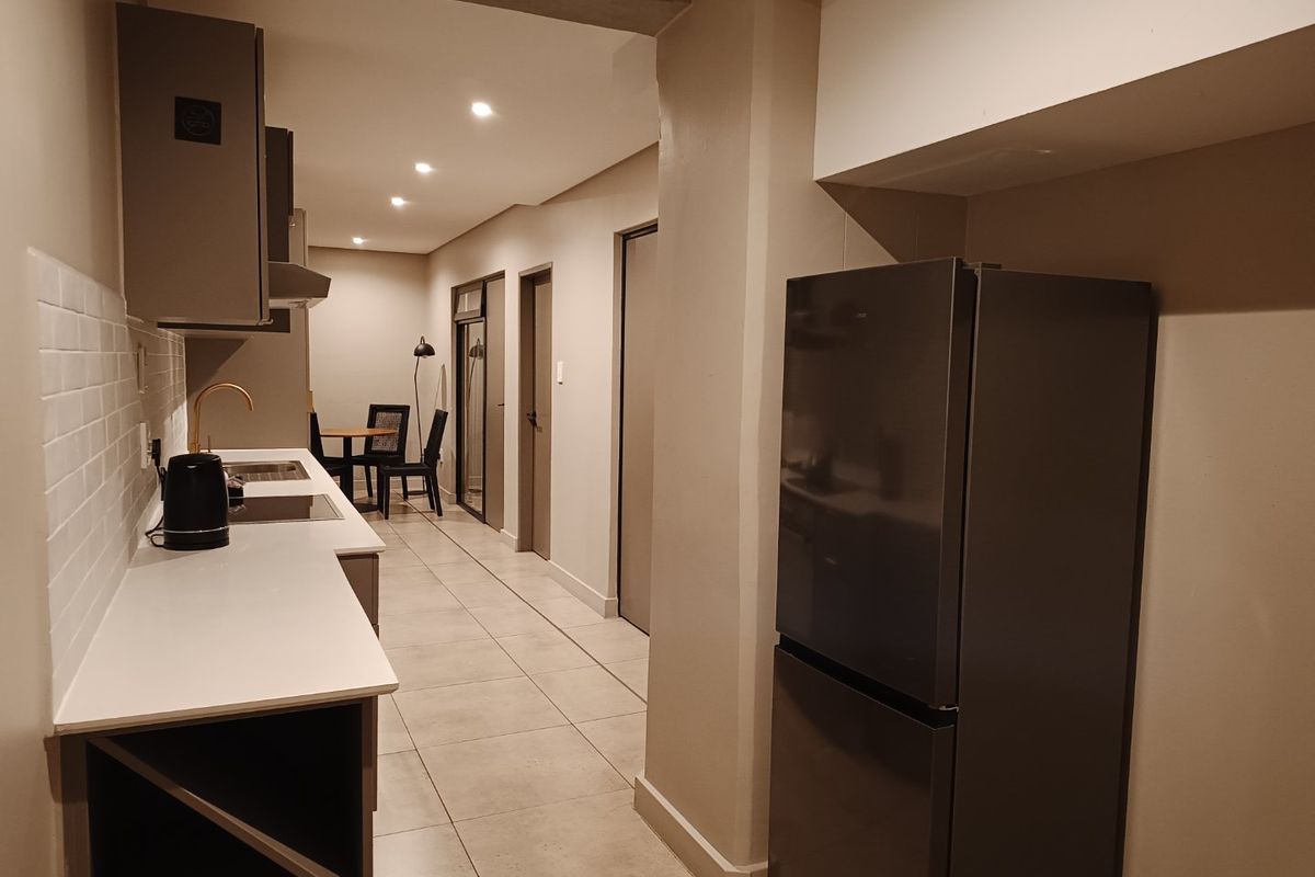 Modern kitchen featuring sleek grey cabinetry, white quartz countertops, subway tile backsplash, and high-quality brass fixtures with integrated lighting.