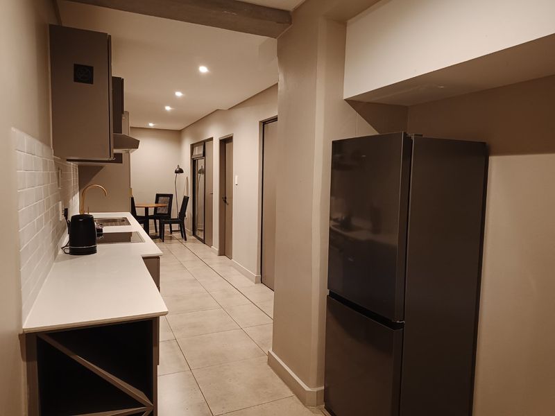 Modern kitchen featuring sleek grey cabinetry, white quartz countertops, subway tile backsplash, and high-quality brass fixtures with integrated lighting.