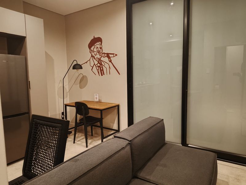 A modern open-plan living area featuring neutral walls, tiled flooring, recessed lighting, and a large sliding glass door providing access to the exterior.