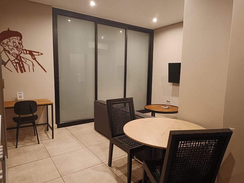A modern living area featuring tiled flooring, recessed lighting, and a sliding glass partition, providing a clean and functional space.