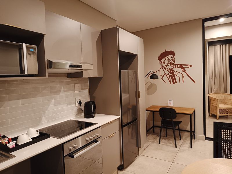 Modern kitchen featuring sleek built-in cabinetry, subway tile backsplash, integrated appliances including an oven and hob, and durable tiled flooring.