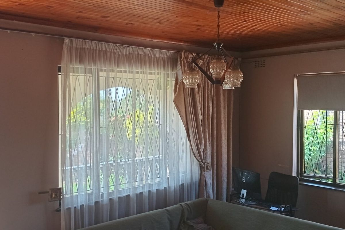 Living room featuring a timber ceiling, security gates on windows, and an intercom system, offering a functional space with natural light.
