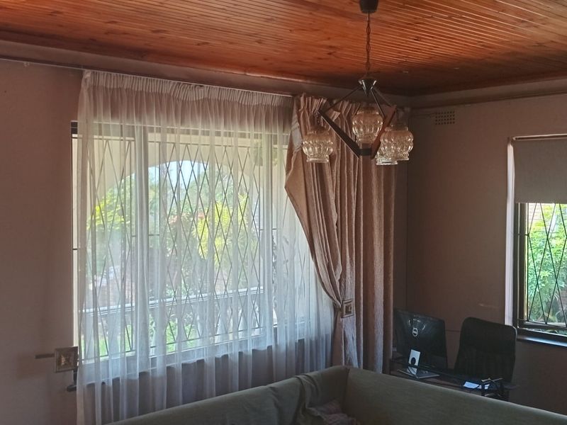 Living room featuring a timber ceiling, security gates on windows, and an intercom system, offering a functional space with natural light.