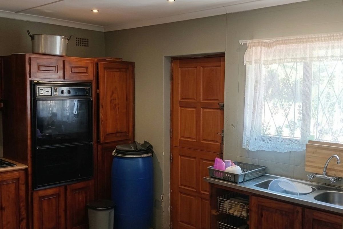 A functional kitchen featuring traditional wooden cabinetry, a built-in oven, a hob, and a double basin sink with a window view.
