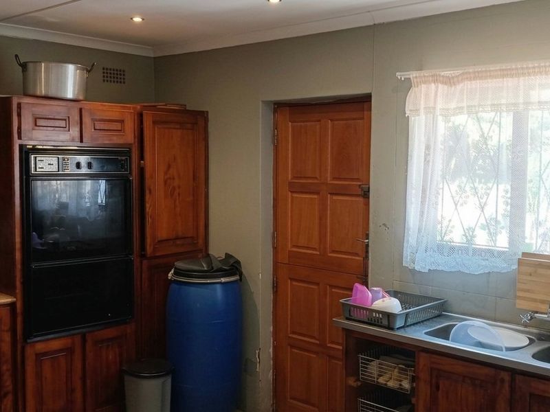 A functional kitchen featuring traditional wooden cabinetry, a built-in oven, a hob, and a double basin sink with a window view.