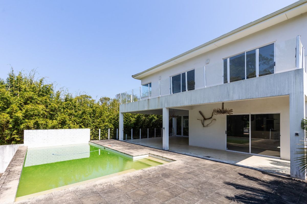 Rear exterior view featuring a swimming pool, covered patio area, and a two-story building facade with glass balcony railings.