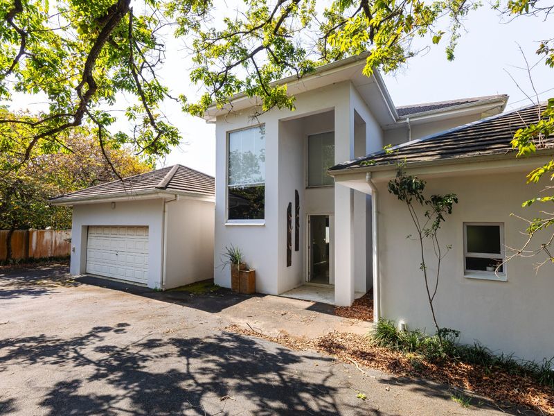 Front elevation of a modern house featuring a double garage, double-volume entrance, and paved driveway area.