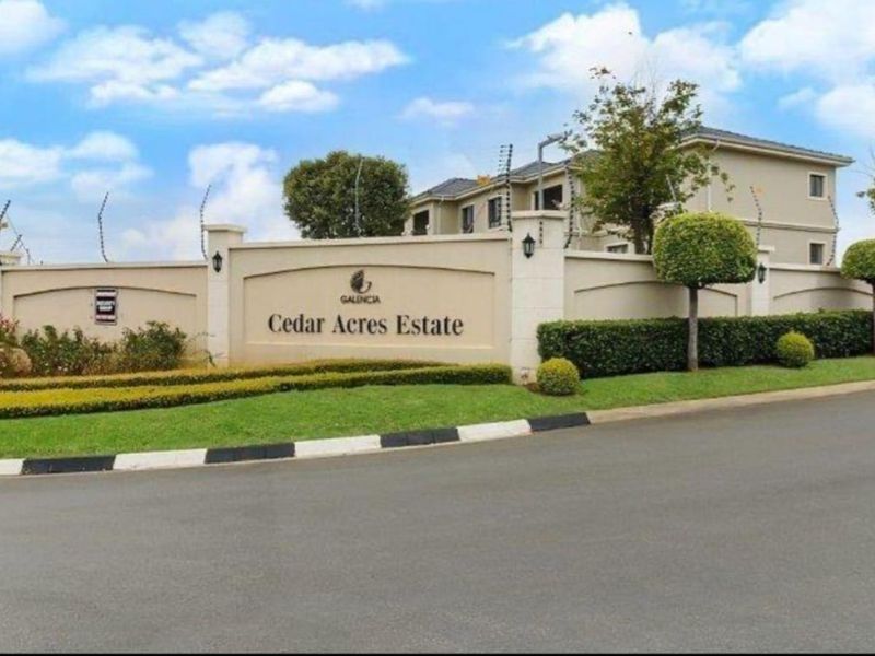 The entrance facade of Cedar Acres Estate featuring a secure perimeter wall, electric fencing, and well-maintained landscaped gardens.