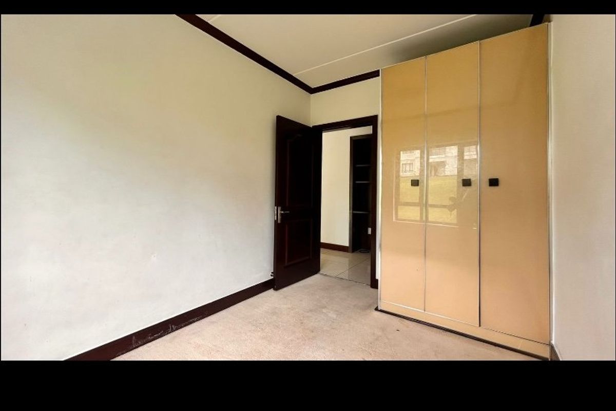 A vacant bedroom featuring built-in wardrobes, carpeted flooring, and dark wood trim accents, offering a neutral space ready for personalization.