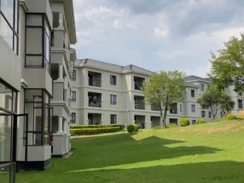 Exterior view of a multi-story apartment complex featuring landscaped green lawns and private balconies.