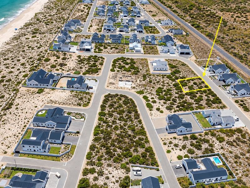 Aerial view of a vacant residential plot located within a coastal estate, featuring established road infrastructure and proximity to the beach.