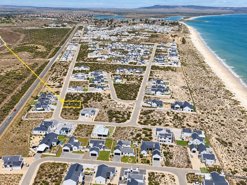 Aerial view of a vacant residential plot situated within a coastal estate, featuring proximity to the beach and established neighborhood infrastructure.