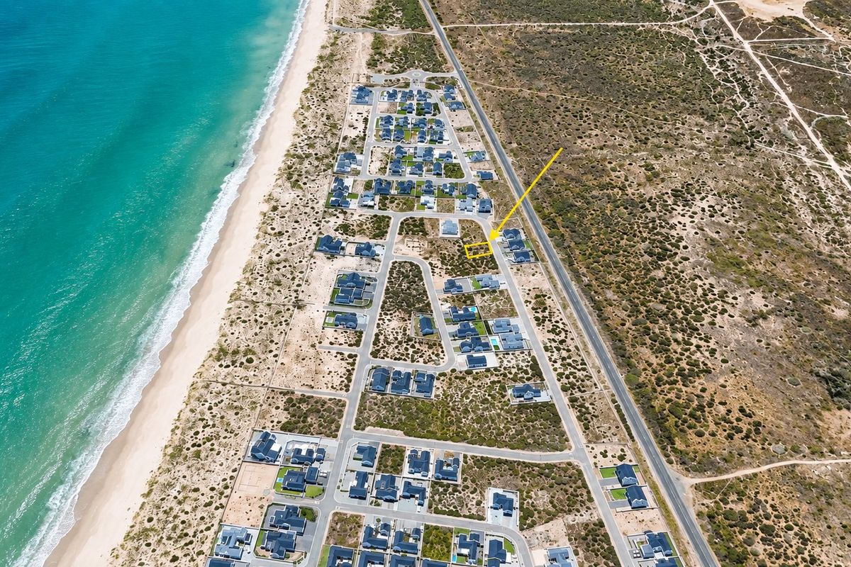 Aerial view of a vacant residential plot within a coastal estate, highlighting its proximity to the beach and established neighborhood infrastructure.