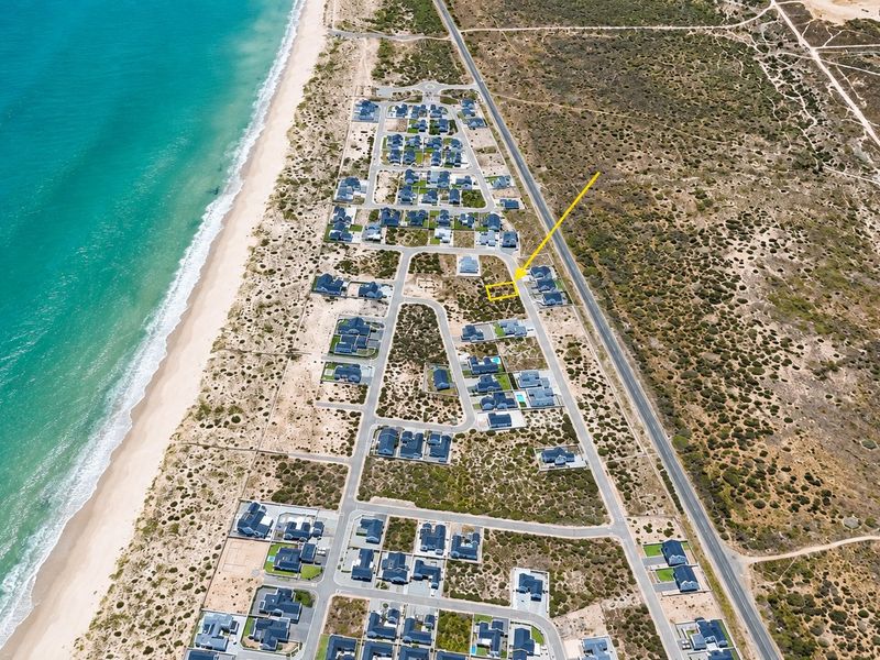 Aerial view of a vacant residential plot within a coastal estate, highlighting its proximity to the beach and established neighborhood infrastructure.