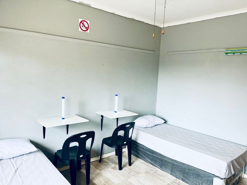 A functional bedroom space featuring wall-mounted desks and tiled flooring, suitable for a dormitory or shared accommodation setup.
