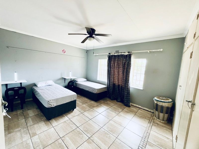 A functional bedroom featuring tiled flooring, a ceiling fan, and built-in storage cupboards.