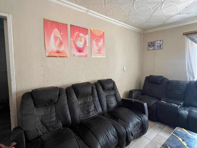 A living room featuring tiled flooring and decorative ceiling tiles, offering a functional space that could benefit from cosmetic updates.