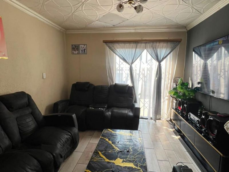 Living room featuring decorative ceiling tiles, tiled flooring, and a sliding glass door with security gate access to the exterior.