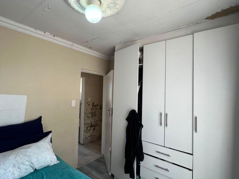 Bedroom featuring a built-in wardrobe and ceiling rose, currently showing significant signs of ceiling and wall surface deterioration requiring maintenance and repair.
