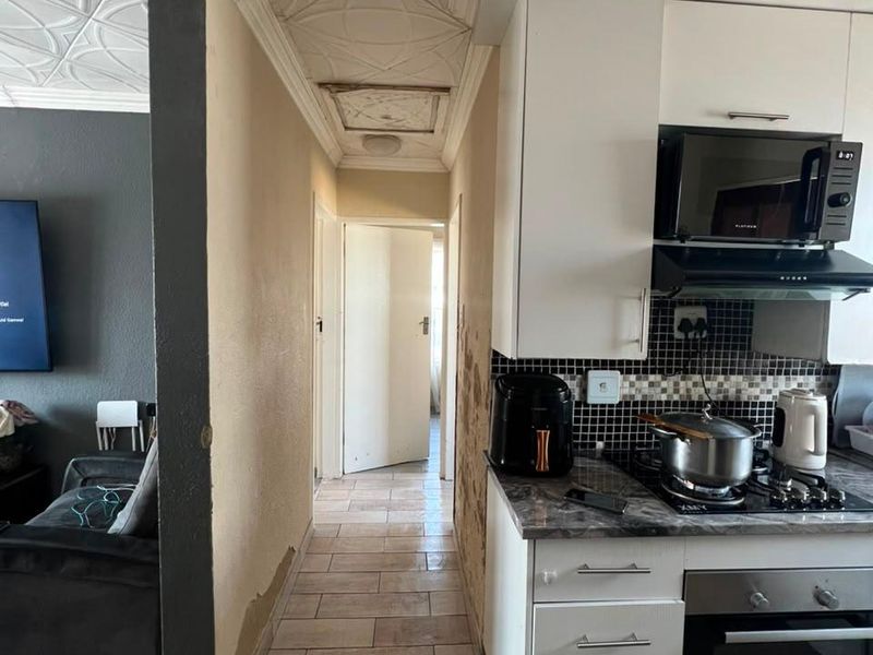 Kitchen area featuring built-in cabinetry, gas hob, and oven, with visible wall and ceiling finish deterioration requiring maintenance.