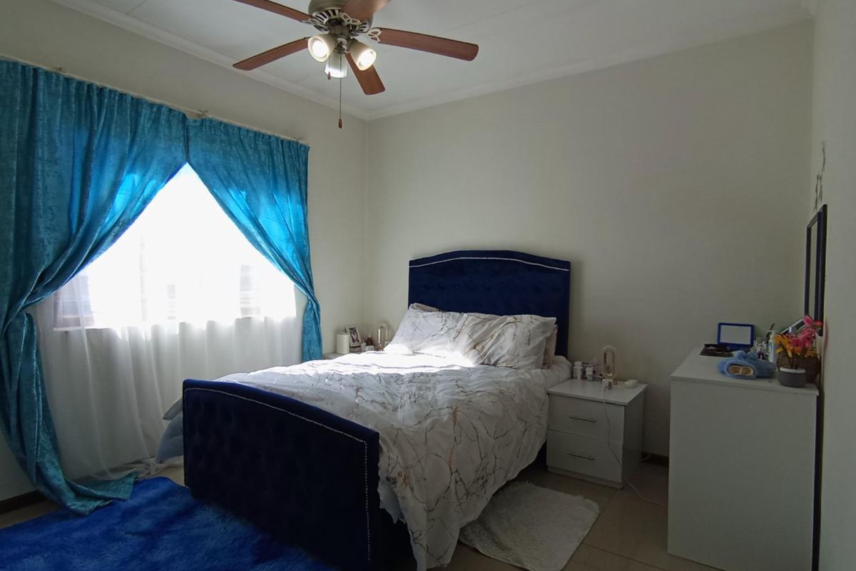 A functional bedroom featuring tiled flooring and a central ceiling fan, providing a comfortable and well-lit living space.