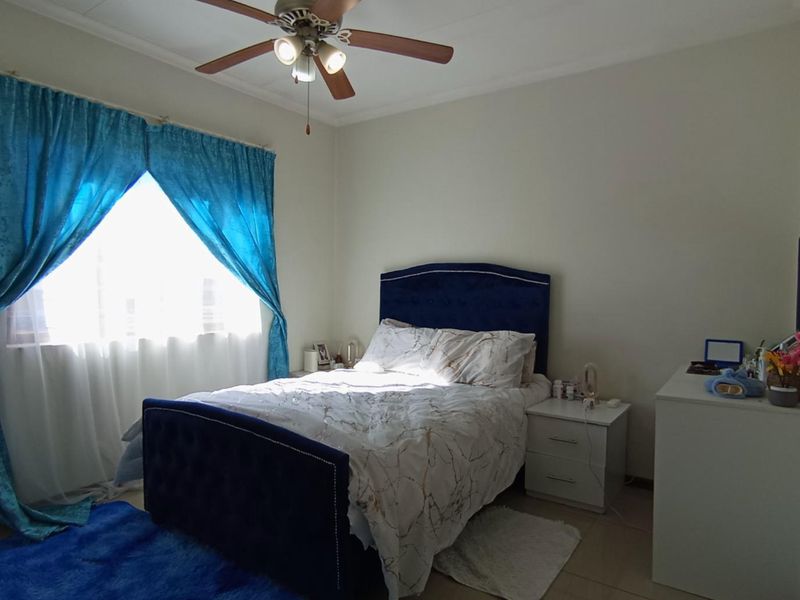 A functional bedroom featuring tiled flooring and a central ceiling fan, providing a comfortable and well-lit living space.