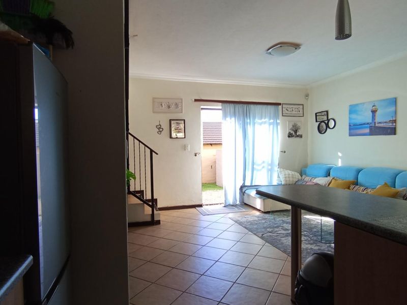 Open plan living area featuring tiled flooring, a breakfast bar, and a sliding glass door providing access to the exterior.
