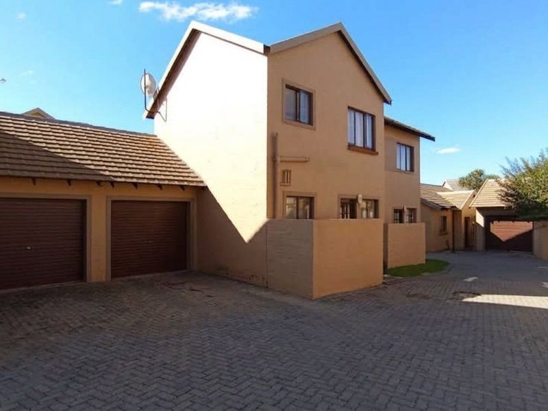 Exterior view of a residential apartment complex featuring a paved driveway and double garage access.
