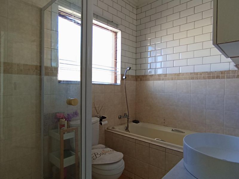 A functional bathroom featuring a glass shower enclosure, a built-in bathtub with subway tile surround, and a modern vessel sink vanity.