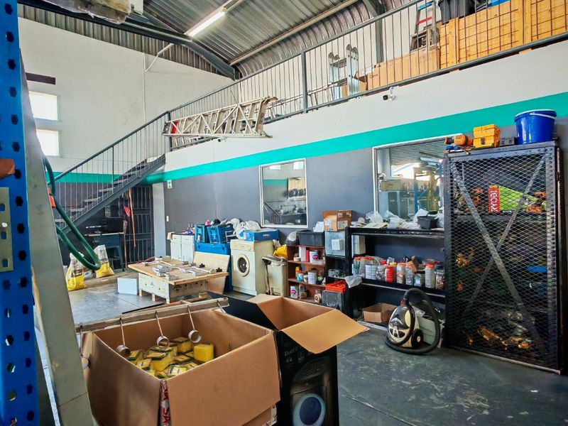 Industrial utility space featuring a mezzanine level with metal staircase, exposed steel roof structure, and functional storage area.