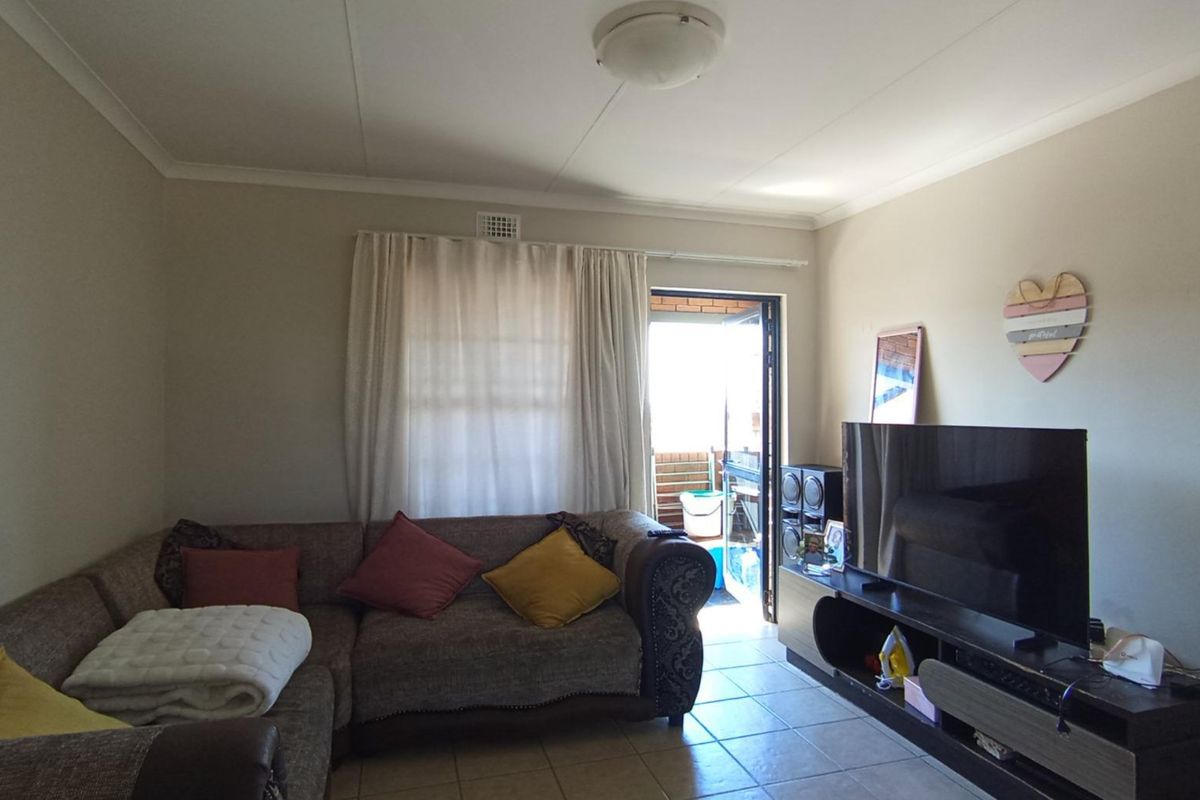 A living room featuring tiled flooring, coved ceilings, and direct access to an outdoor balcony area.