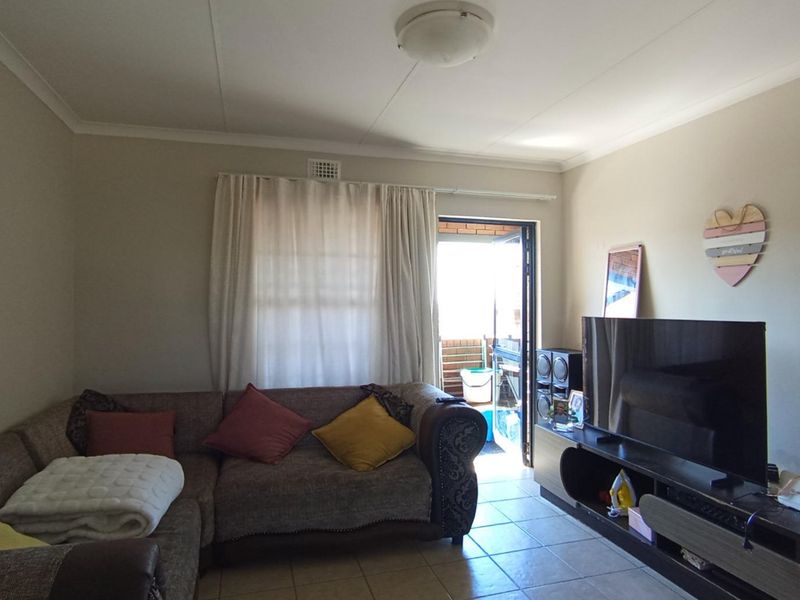 A living room featuring tiled flooring, coved ceilings, and direct access to an outdoor balcony area.
