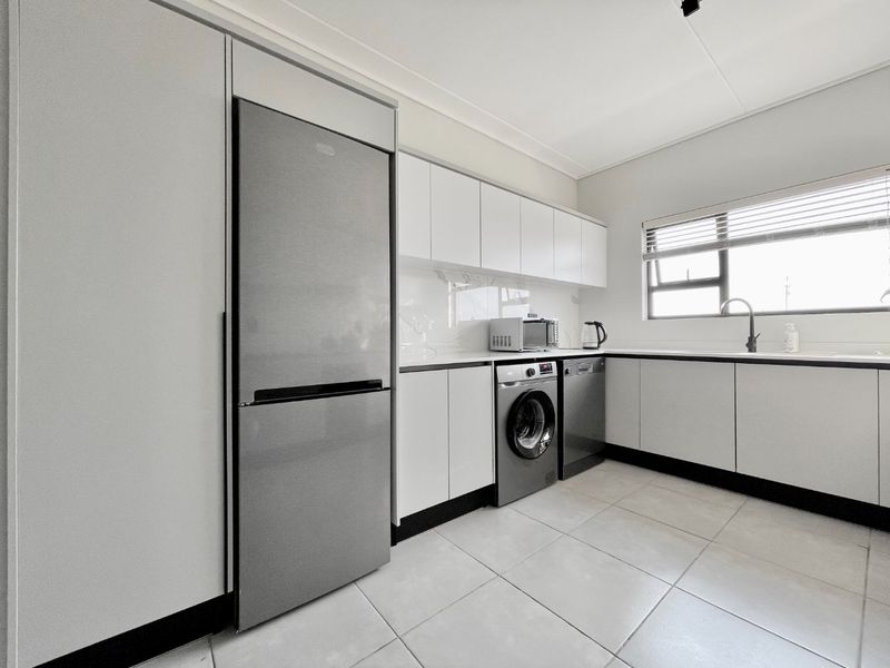 Modern kitchen featuring sleek white cabinetry, tiled flooring, integrated appliances, and a functional layout with ample counter space and natural light.