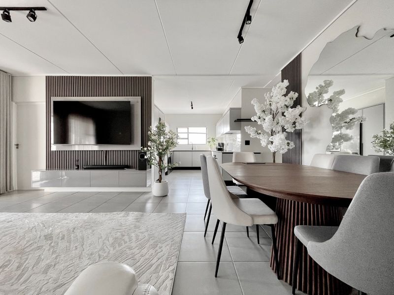 Modern open-plan living and dining area featuring contemporary slatted wood wall paneling, sleek built-in cabinetry, and high-quality tiled flooring throughout.